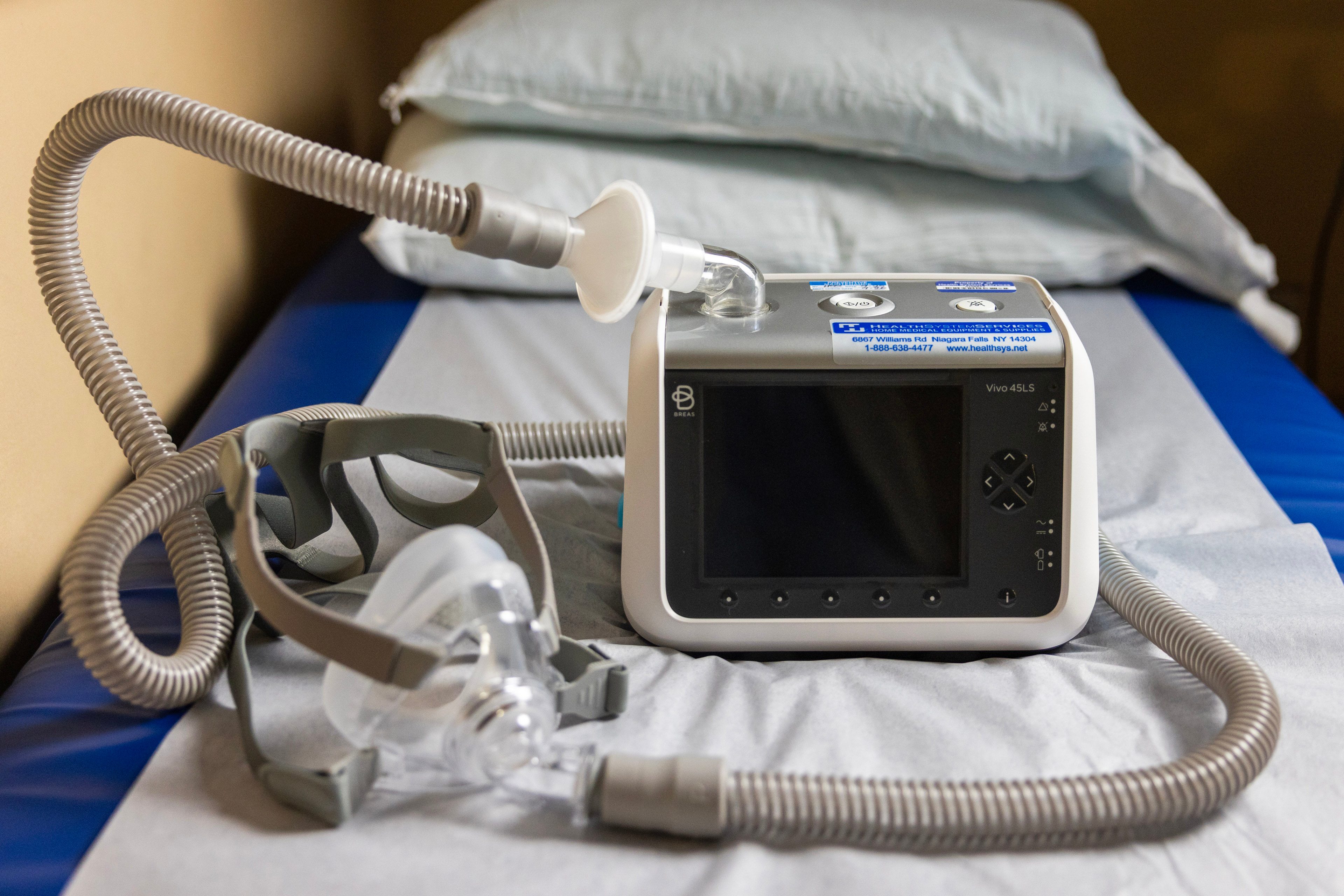 A ventilator sits on a gurney in a hospital exam room
