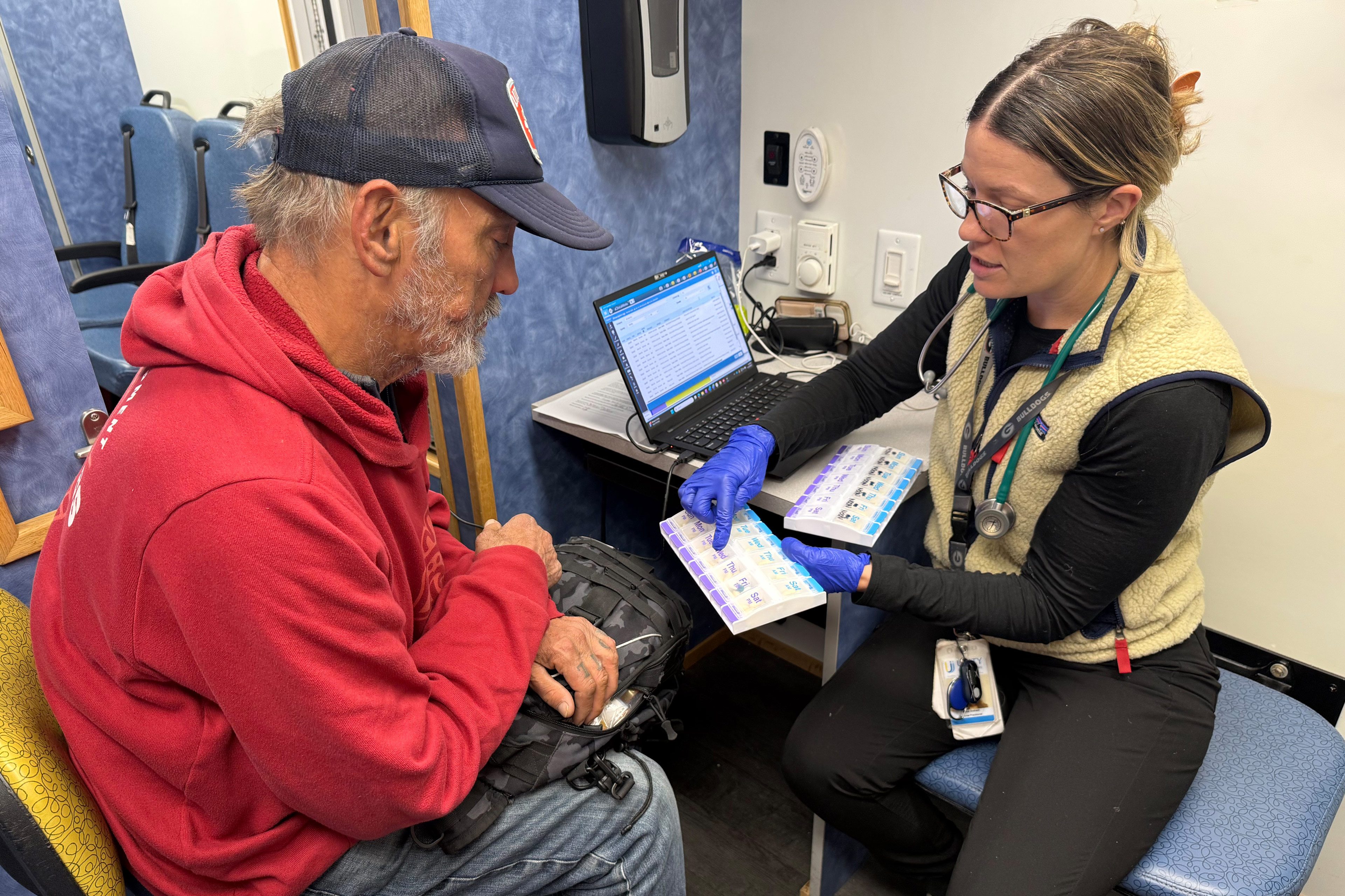 A photo of woman showing a man a pill organizer.