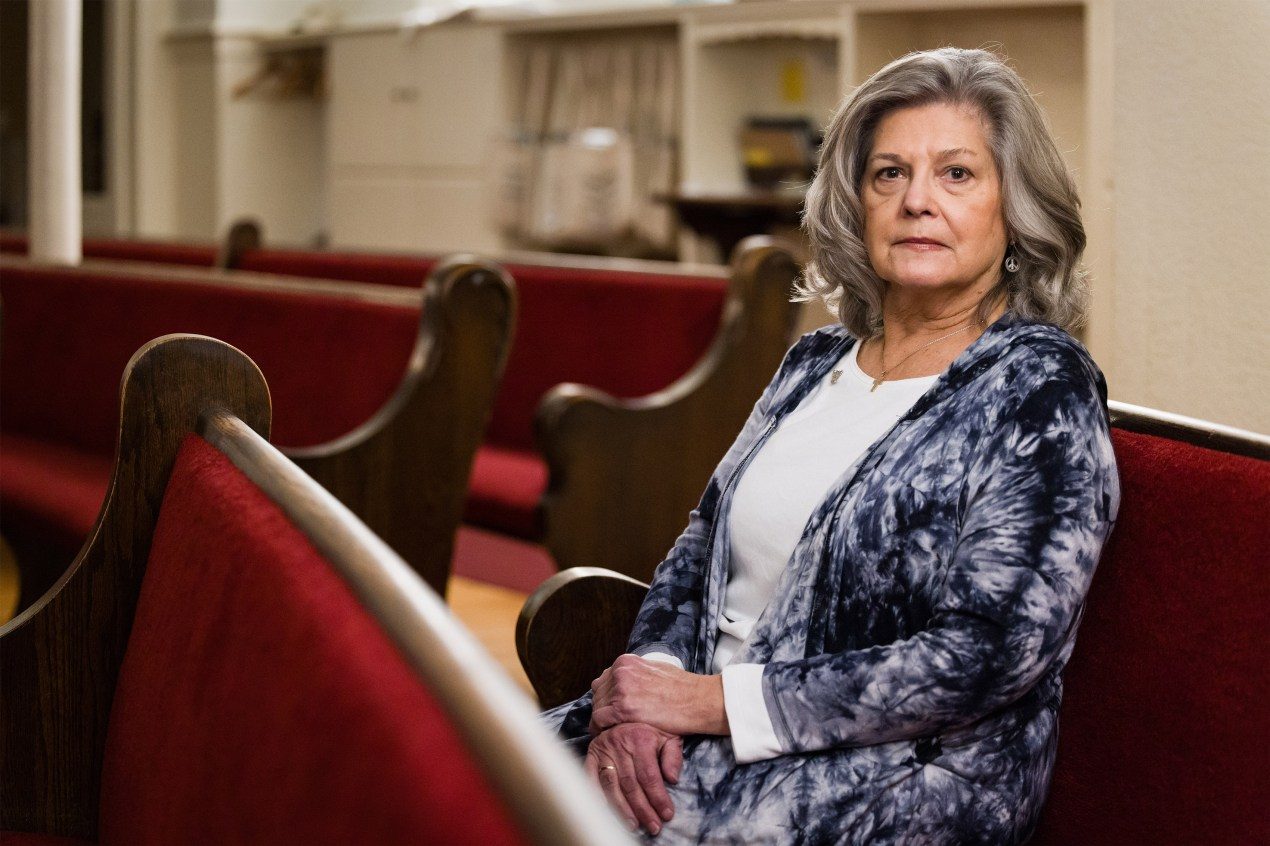 A woman sits in a church pew.